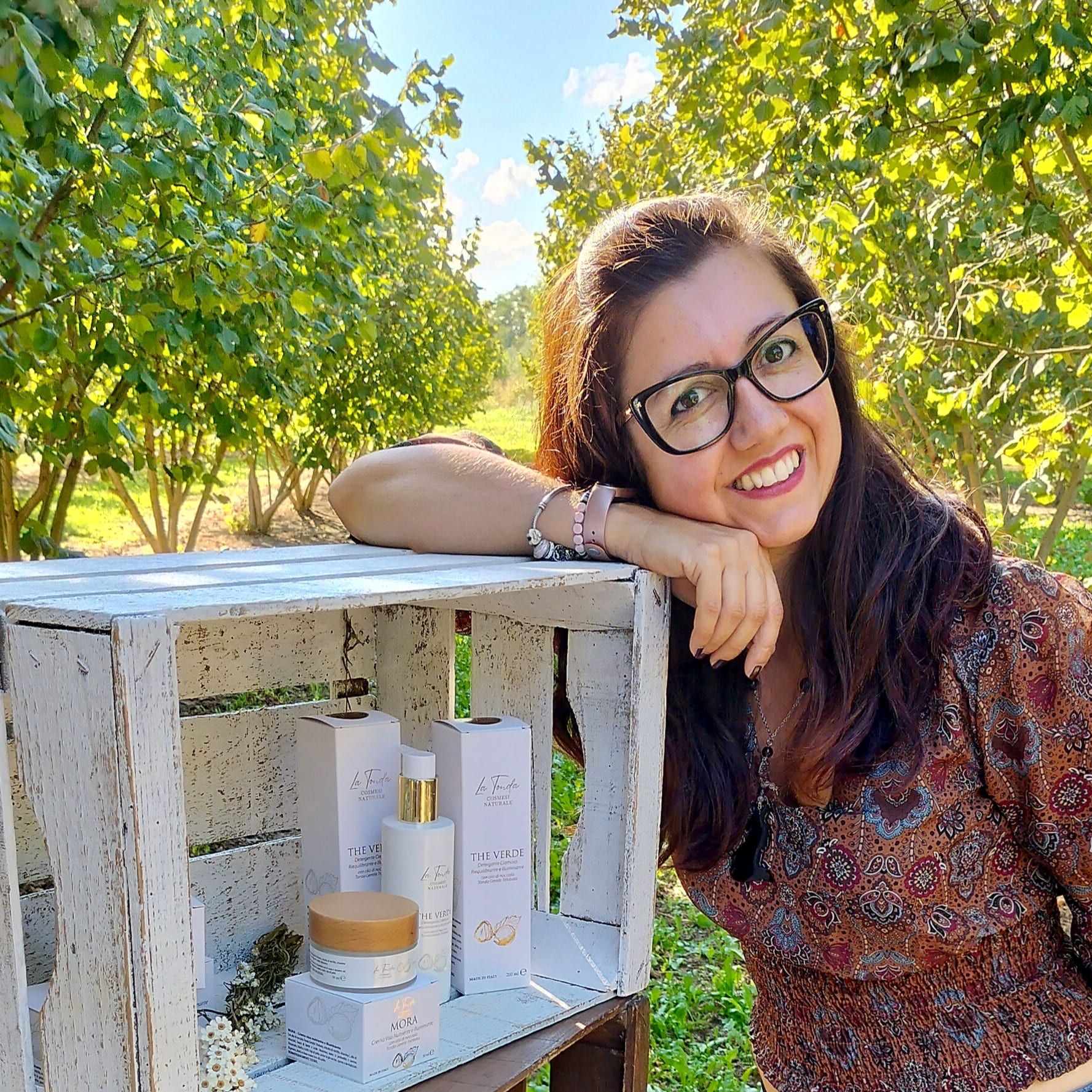 Foto profilo di La Tonda cosmesi. Marilyne con i prodotti di skincare nel noccioleto